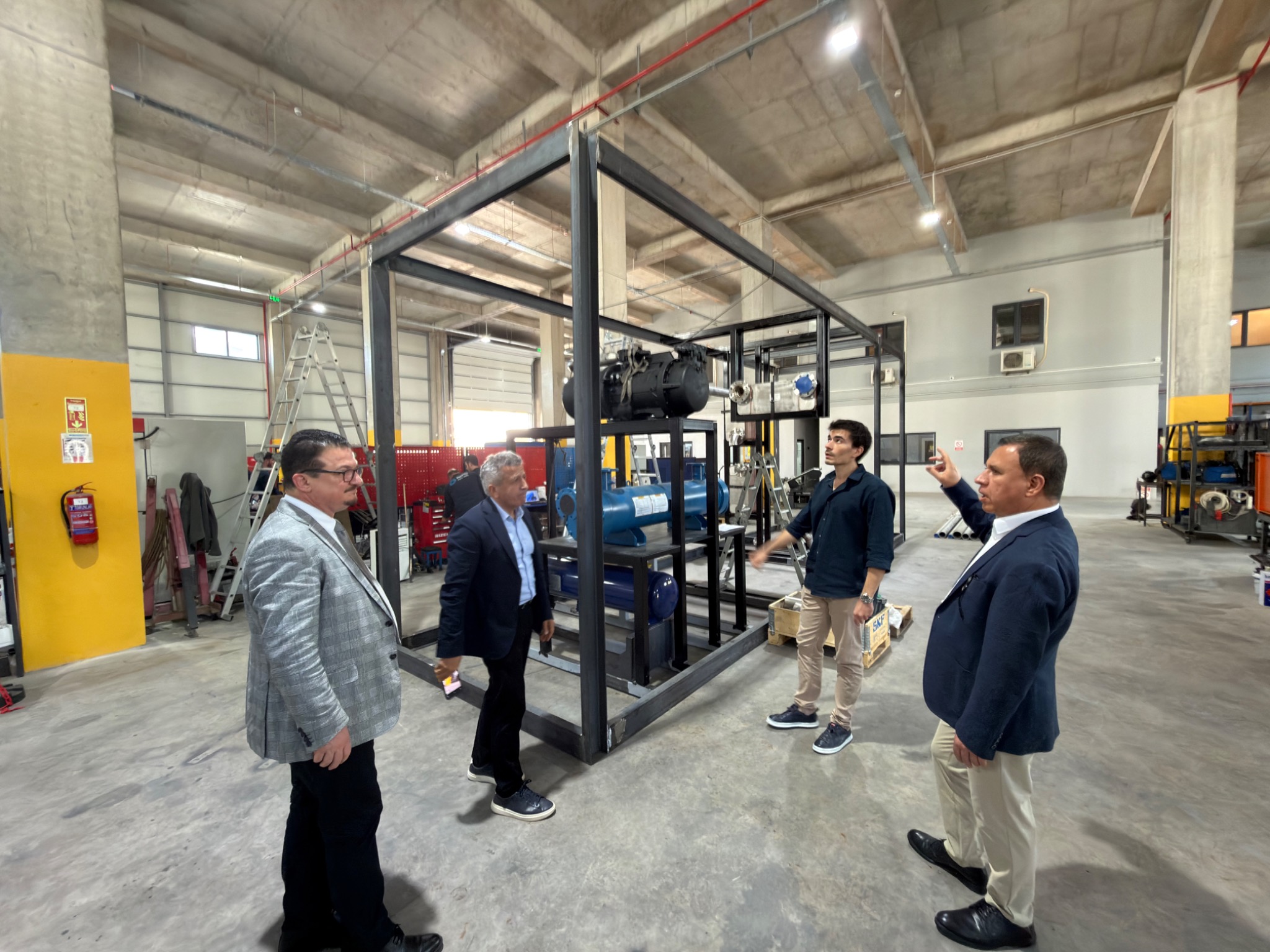 The visiting group reviewing equipment on the workshop floor.
