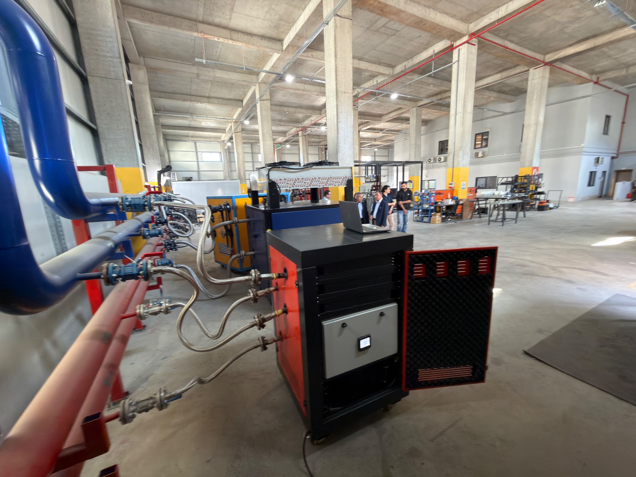 Equipment cabinets, pipework and a control panel inside the workshop.