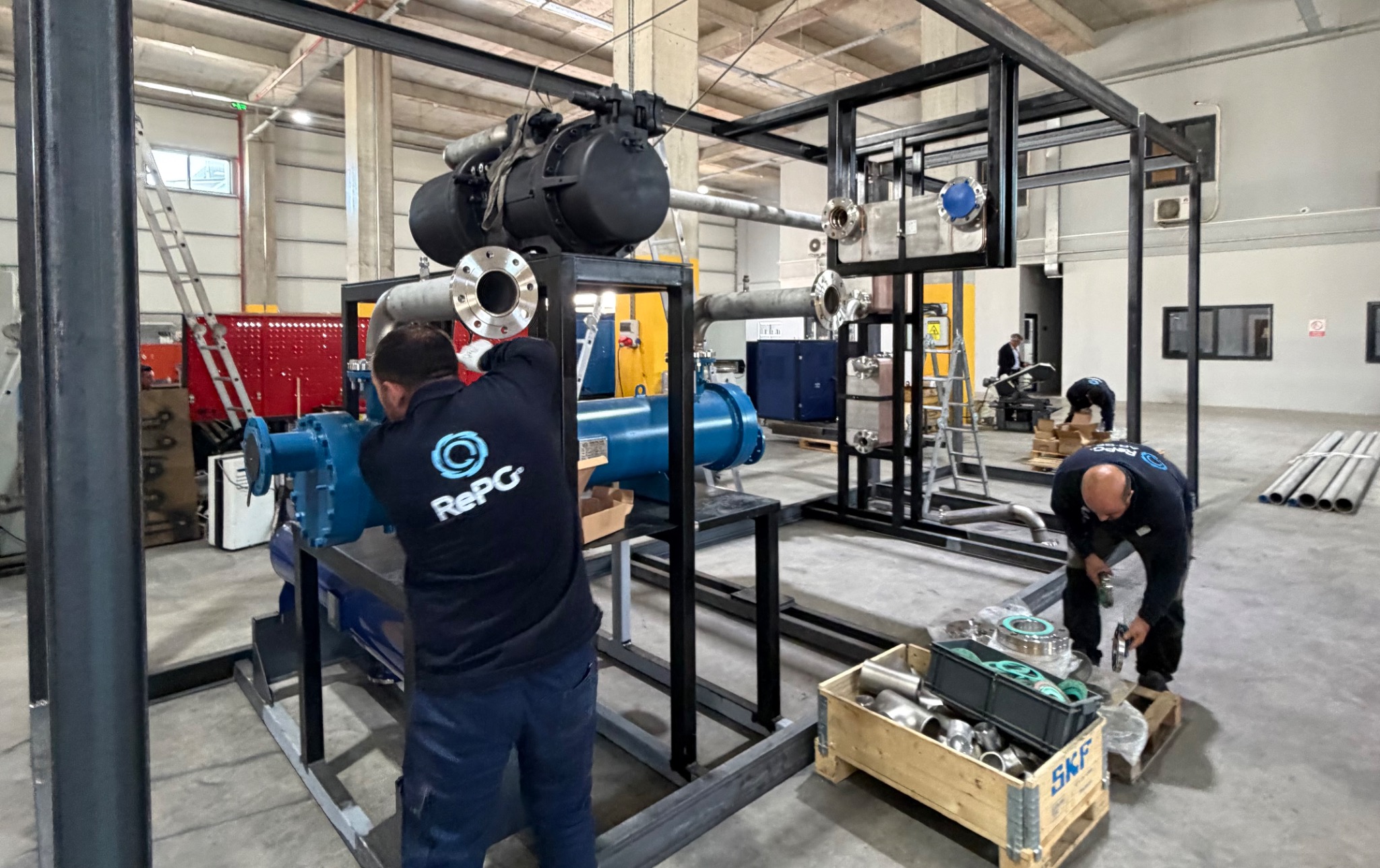 Technicians working around equipment and components in the assembly area.