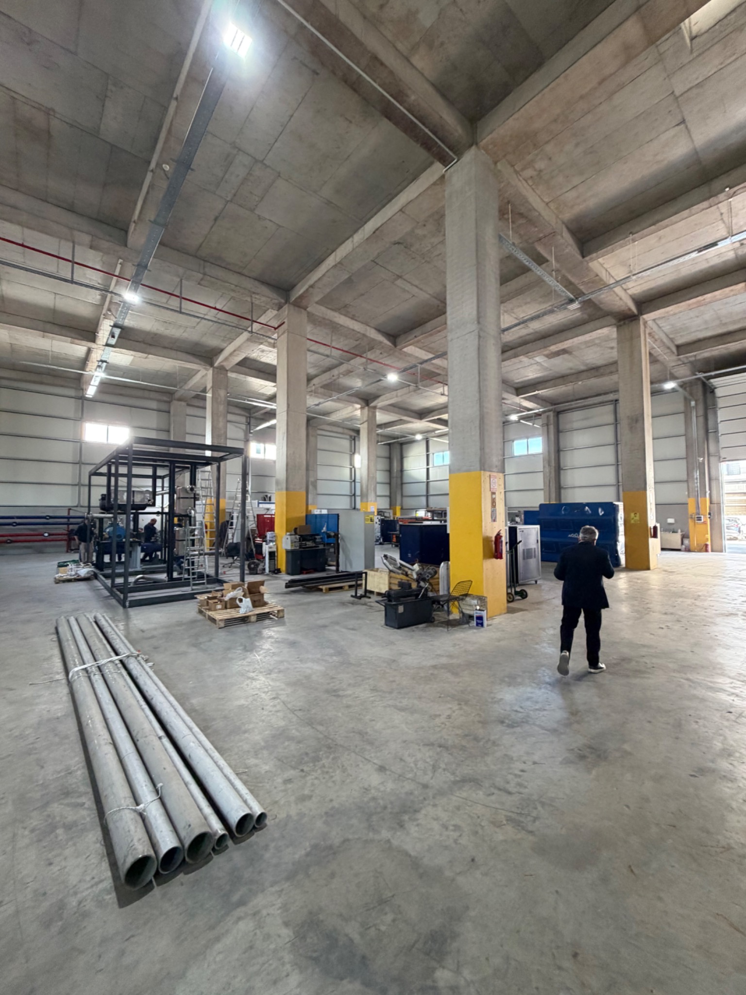 Workshop floor with metal pipework, equipment frames and work areas.