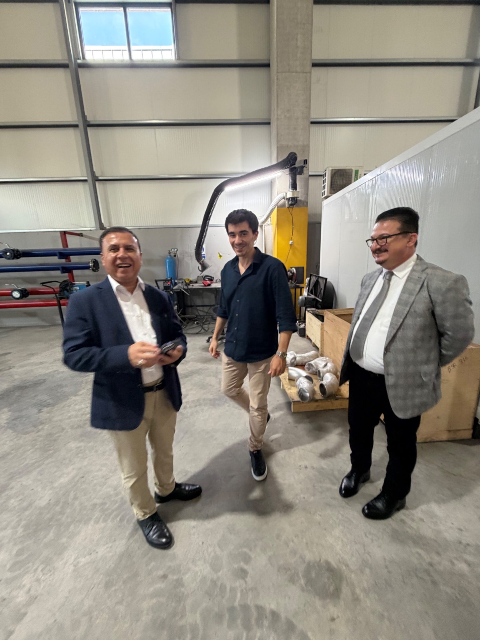 Informal discussion with the visiting delegation beside workshop equipment.