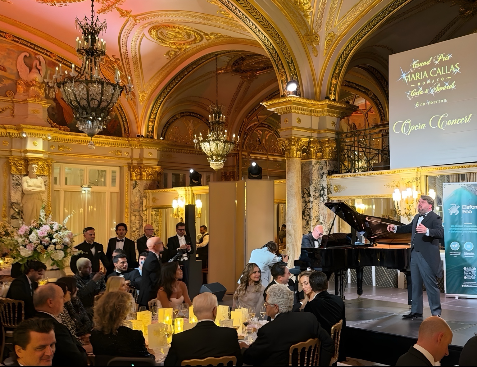 A singer and pianist performing for the gala audience beneath the Salle Empire chandeliers