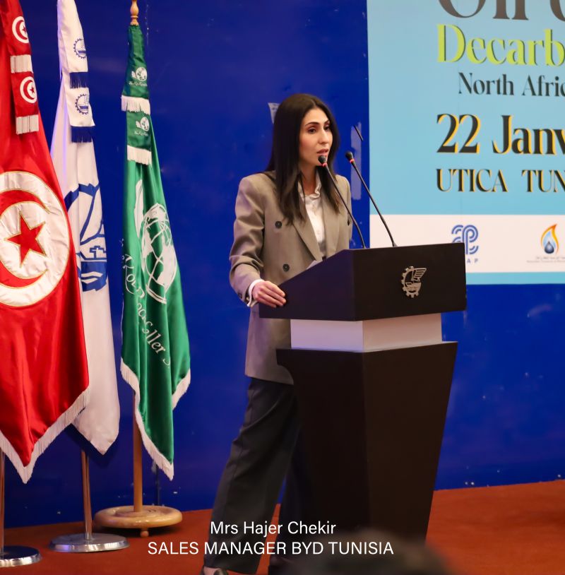 A speaker presenting beside the dated Oil & Gas Decarbonization event screen